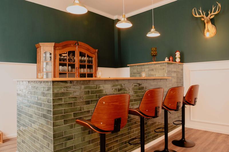 Grüne Bar mit Hockern und Geweihdeko an der Wand